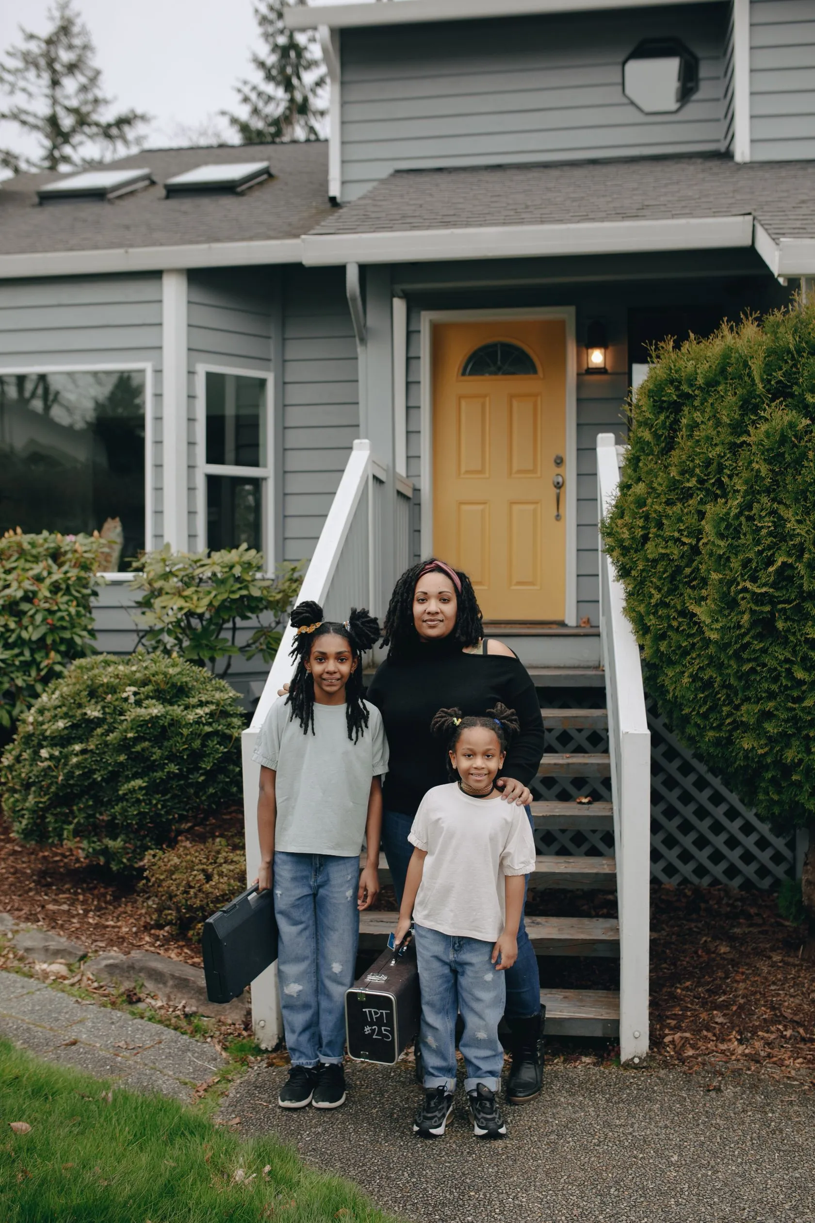 A family stands on the steps of their home.