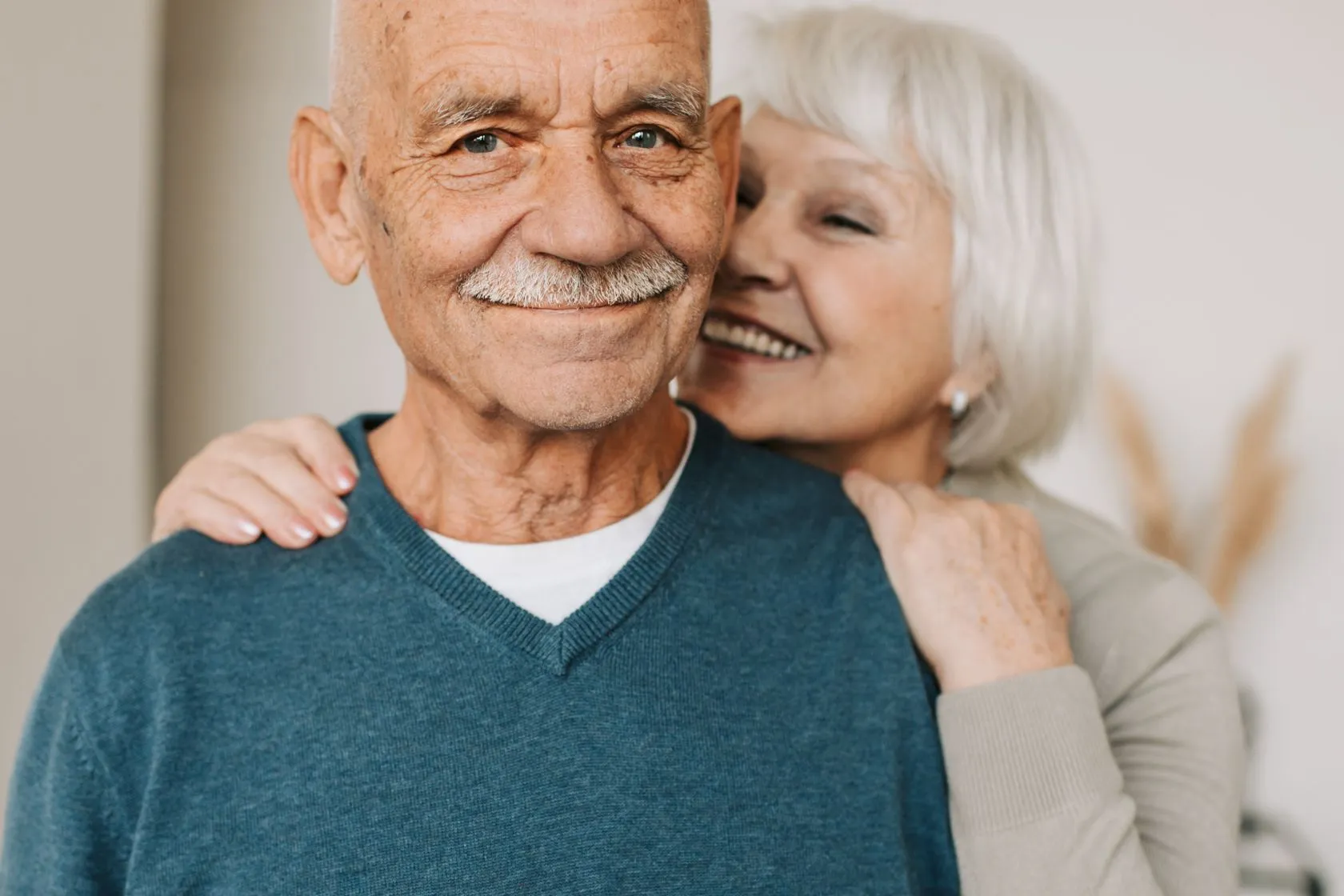 An older couple stand close together, relaxed and content.